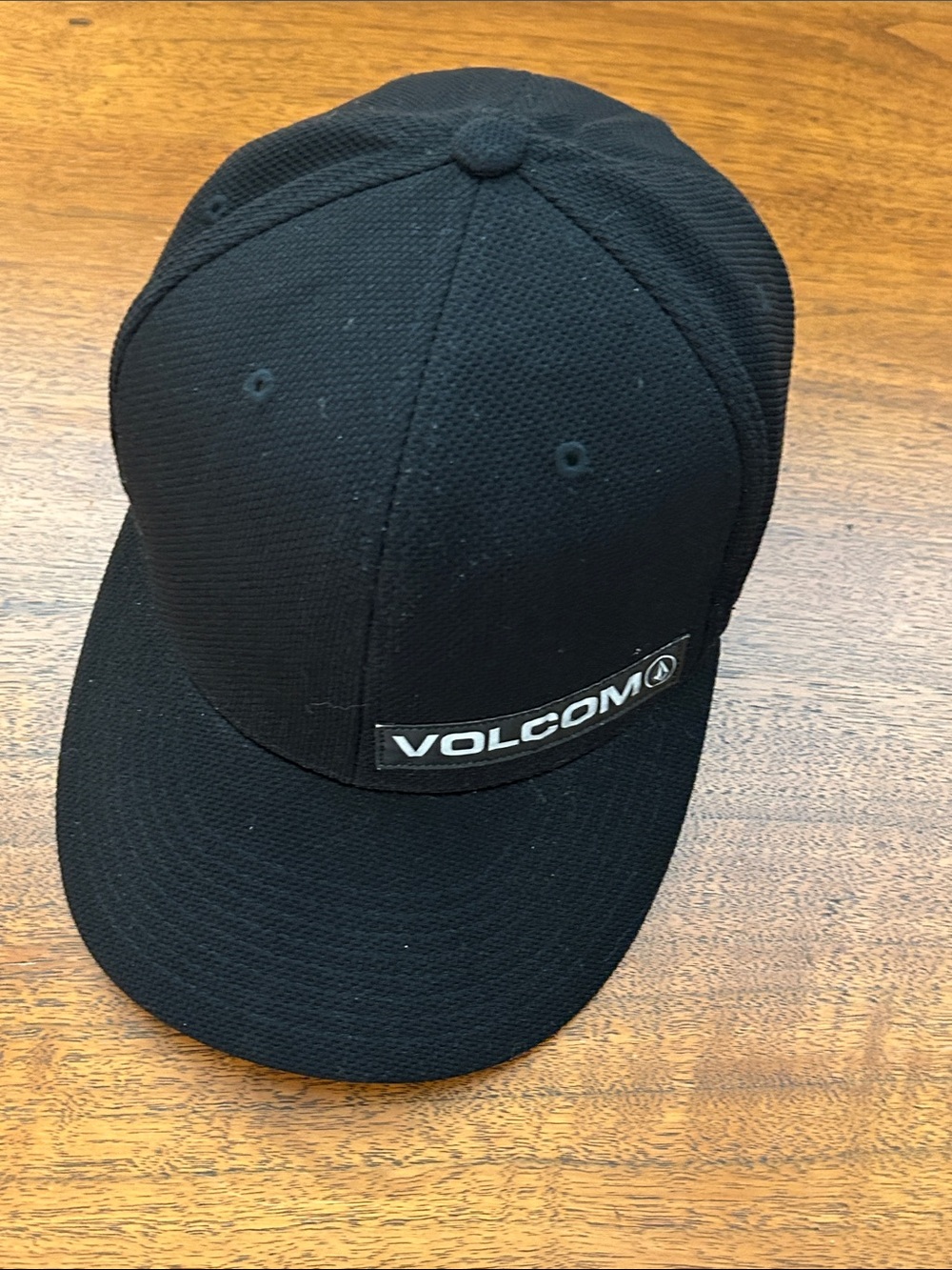 Volcom Flexfit Poly/Rayon/Spandex Black Cap with Reflective Name Logo on Front.